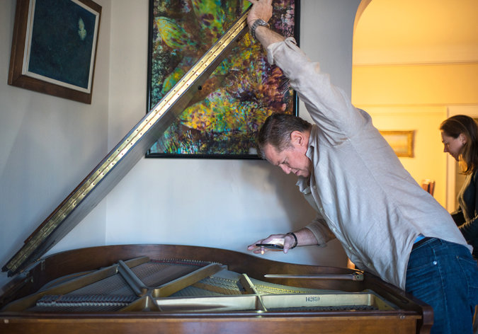 Mr. Berman inspects a baby grand piano that is not moving with Dr. Harrison-Ross to her new digs. Credit Emon Hassan for The New York Times